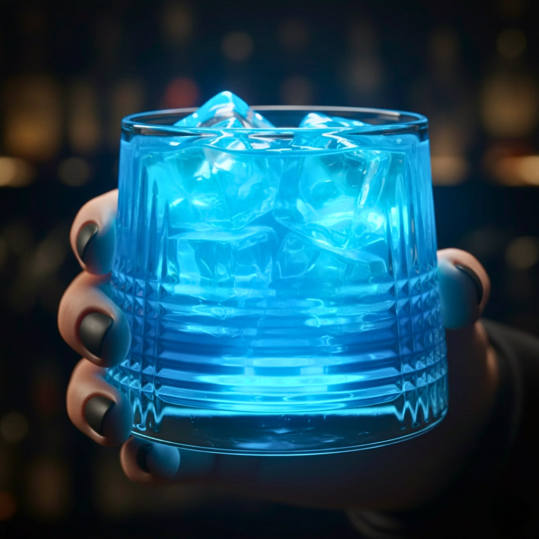 Hand holding a glass with blue glowing liquid against a blurred background